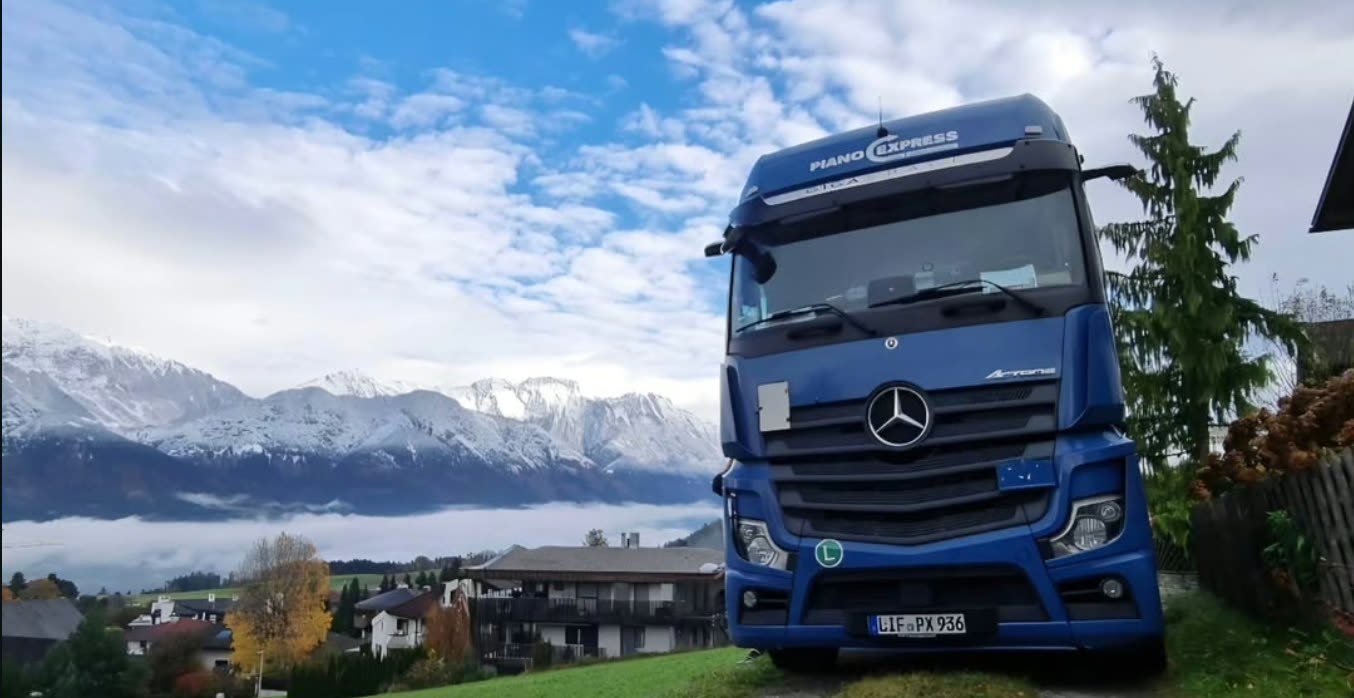 Camion Piano-Express devant un panorama alpin – en route vers la France