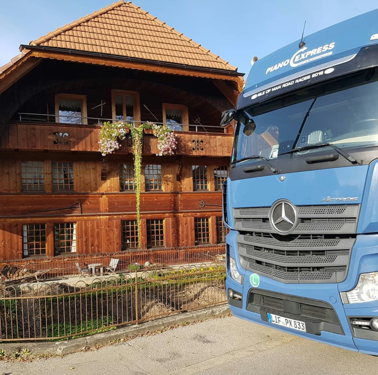 Piano-Express truck in front of a country house – piano transport in the Munich area