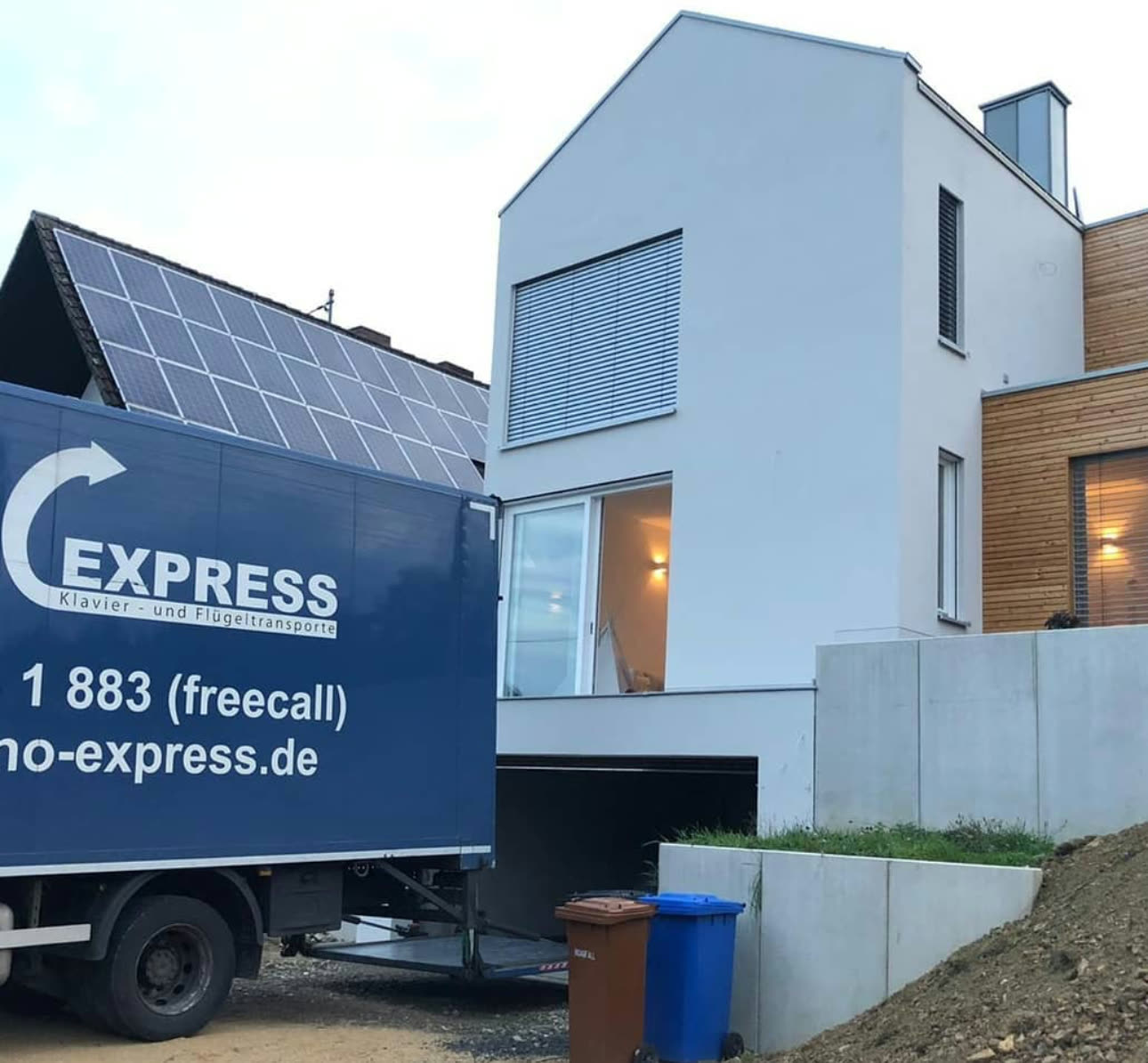 Piano-Express truck delivering to a modern house with a solar system
