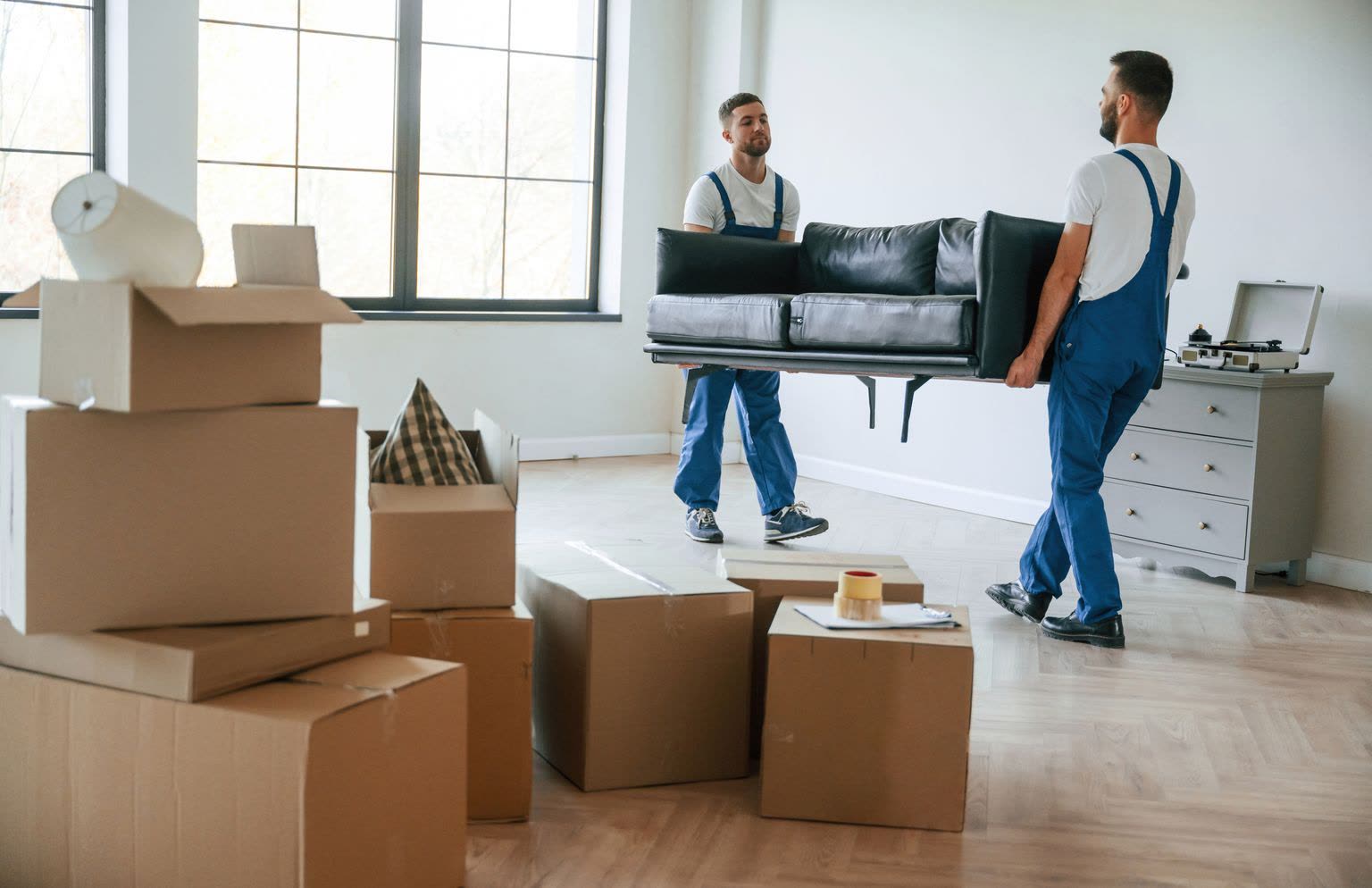 Dos empleados de Piano-Express transportan un sofá por una vivienda